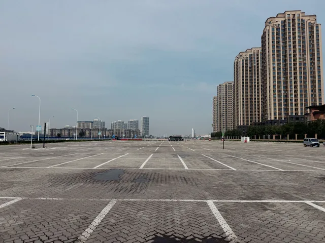 Empty parking lot surrounded by tall residential buildings in an urban setting under a clear sky. How to screen Level 1 EV charging resident fit